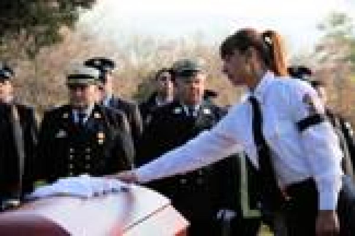 A paramedic student who was in Jon's medic class places her gloves on the casket