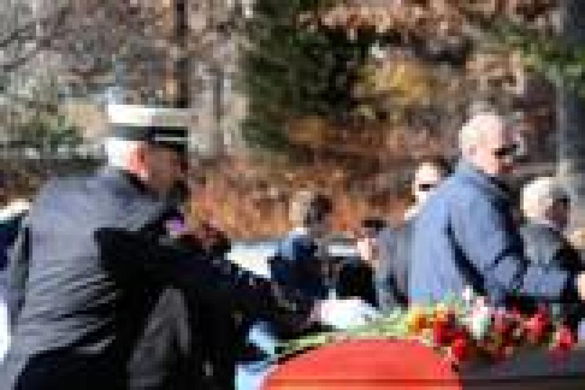Auxiliary members place roses on the casket as a final goodbye to a brother take