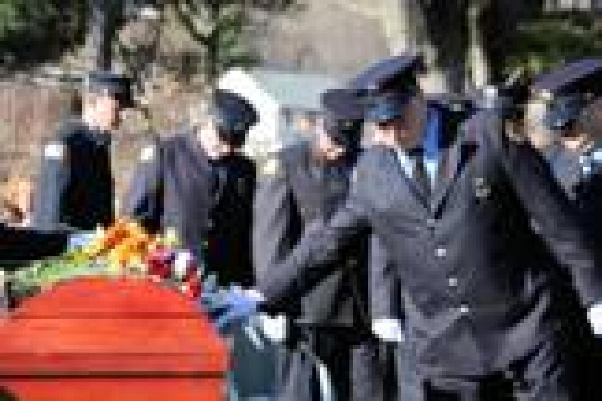 Auxiliary members place roses on the casket as a final goodbye to a brother take