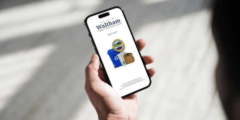 Left hand holding an iphone featuring the cover page of our 2026 trash & recycling brochure